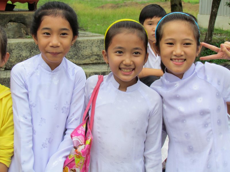 Joyful Vietnamese girls wearing their white Ao Dai's to Sunday Mass